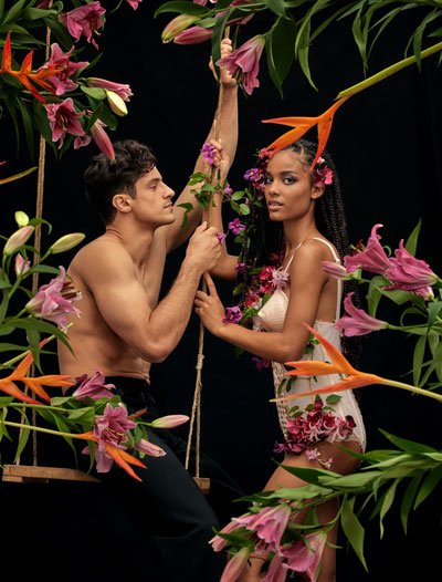 Male and female model with flowers on dark background